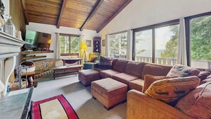 Una sala de estar acogedora con techo de madera, ventanas amplias, chimenea y un espacio de descanso confortable.