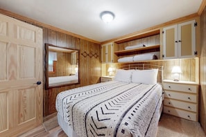 Ein Schlafzimmer mit Bett, Holzschrank, Nachttischen und einem Spiegel.