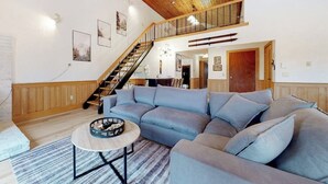 A living room with a sectional sofa, a round coffee table, and a staircase leading to an upper level. - Mountain view, 2-story condo with fireplace & pool table - 1 mile to Story Land (Bartlett)