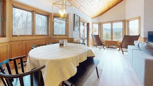 A dining area with a round table, chairs, a bench, and a sofa. - Mountain view, 2-story condo with fireplace & pool table - 1 mile to Story Land (Bartlett)
