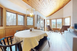 A dining area with a round table, chairs, a bench, and a sofa. - Mountain view, 2-story condo with fireplace & pool table - 1 mile to Story Land (Bartlett)
