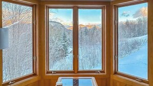 A room with three large windows offering a view of a snowy landscape. - Mountain view, 2-story condo with fireplace & pool table - 1 mile to Story Land (Bartlett)