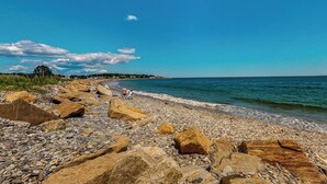 Ein felsiger Strand mit großen Felsen und blauem Himmel.