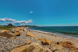 Ein felsiger Strand mit großen Felsen und blauem Himmel.