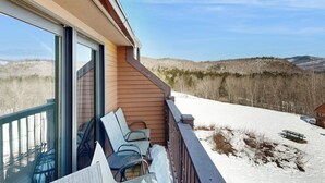 Ein Balkon mit Blick auf schneebedeckte Hügel und einen klaren Himmel.