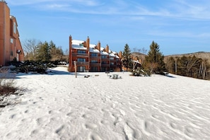 A multi-story building with a snow-covered ground, a picnic table, and a bench. - Mountain stunner with pools, hot tub, tennis, grilling area, & game tables (Bartlett)