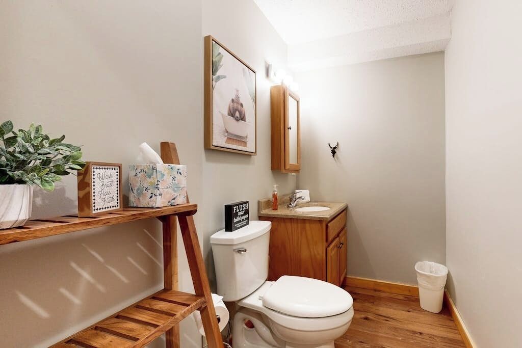 Une petite salle de bain avec des toilettes, un lavabo et des étagères en bois.