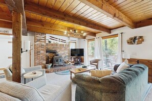 Ein gemütliches Wohnzimmer mit Kamin, Fernseher und großem Fenster.