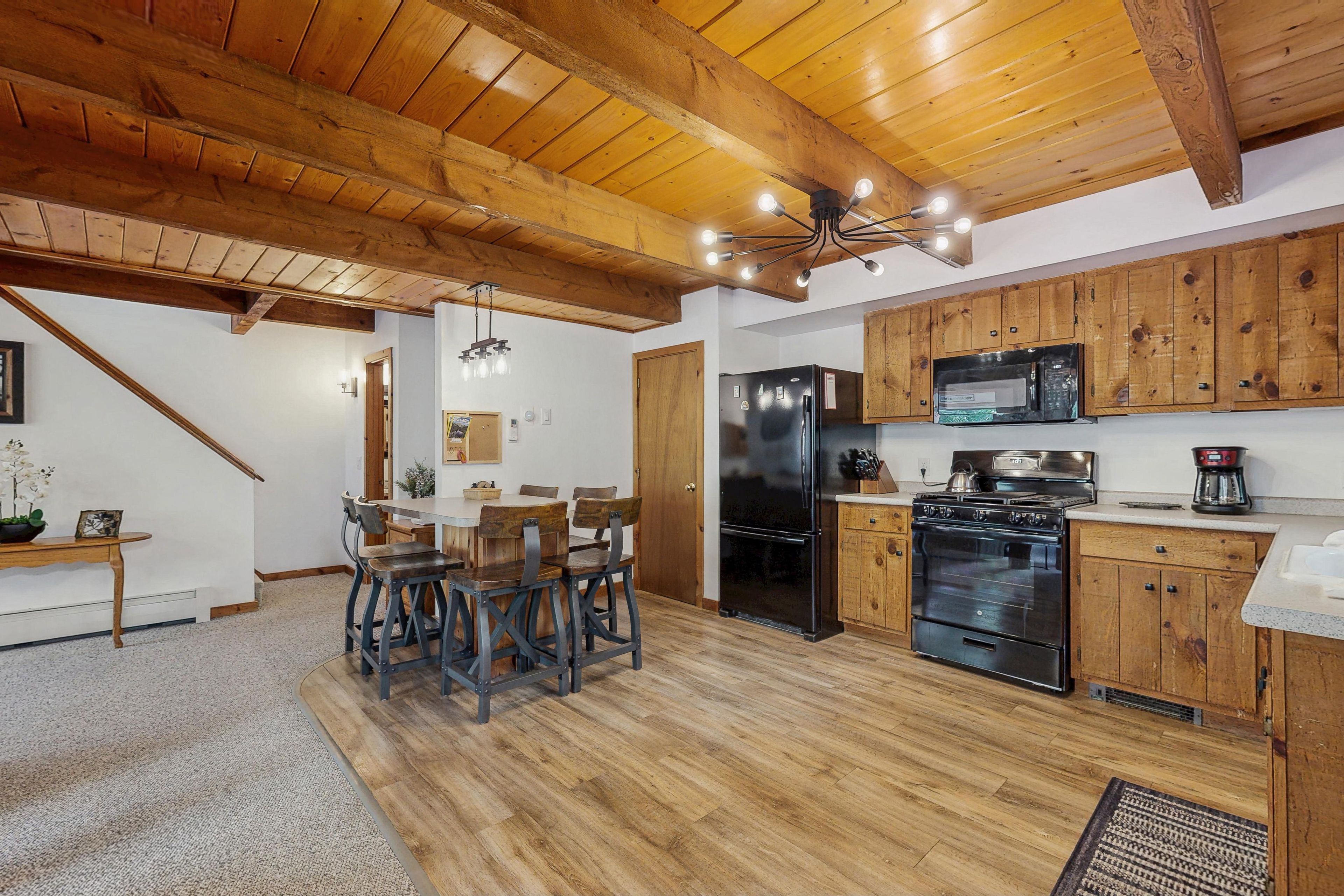 A kitchen with wooden cabinets, a black refrigerator, a microwave, and a stove.