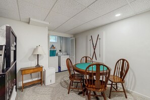 A compact room with a round table, four wooden chairs, a lamp, a washing machine, and a dryer. - Townhouse with mini-split A/C, wood-burning stove and pool access (Bartlett)