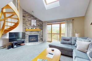 A living room with a TV, fireplace, sofa, and a spiral staircase. - Mountain view condo with indoor & outdoor pools, hot tub, & tennis (Bartlett)