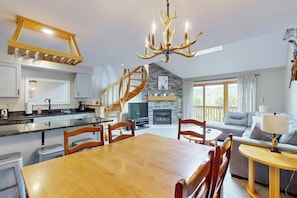 A modern kitchen with a wooden staircase, a dining area with a wooden table and chairs, a fireplace, and a living room with a sofa and a lamp. - Mountain view condo with indoor & outdoor pools, hot tub, & tennis (Bartlett)