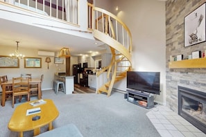 A spacious living room with a wooden staircase, a fireplace, and a television. - Mountain view condo with indoor & outdoor pools, hot tub, & tennis (Bartlett)
