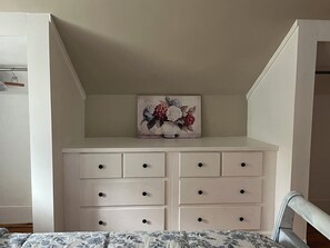 A bedroom with a bed, a white dresser with drawers, and a painting of flowers on the wall. - Bring Fido! Spacious 2 family home 7-bedroom 5 bathroom in charming Chatham. (Chatham)