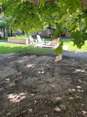 A garden area with a wooden planter, a seating area with chairs, and a lawn. - Bring Fido! Spacious 2 family home 7-bedroom 5 bathroom in charming Chatham. (Chatham)