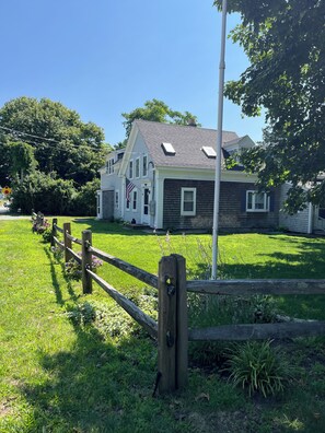 A two-story house with a front lawn and a wooden fence. - Bring Fido! Spacious 2 family home 7-bedroom 5 bathroom in charming Chatham.🐶⛱️🛥️ (Chatham)