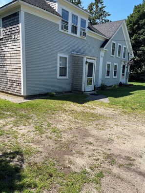 A two-story house with a front door, a garage door, and a small front yard with grass and gravel. - Bring Fido! Spacious 2 family home 7-bedroom 5 bathroom in charming Chatham. (Chatham)