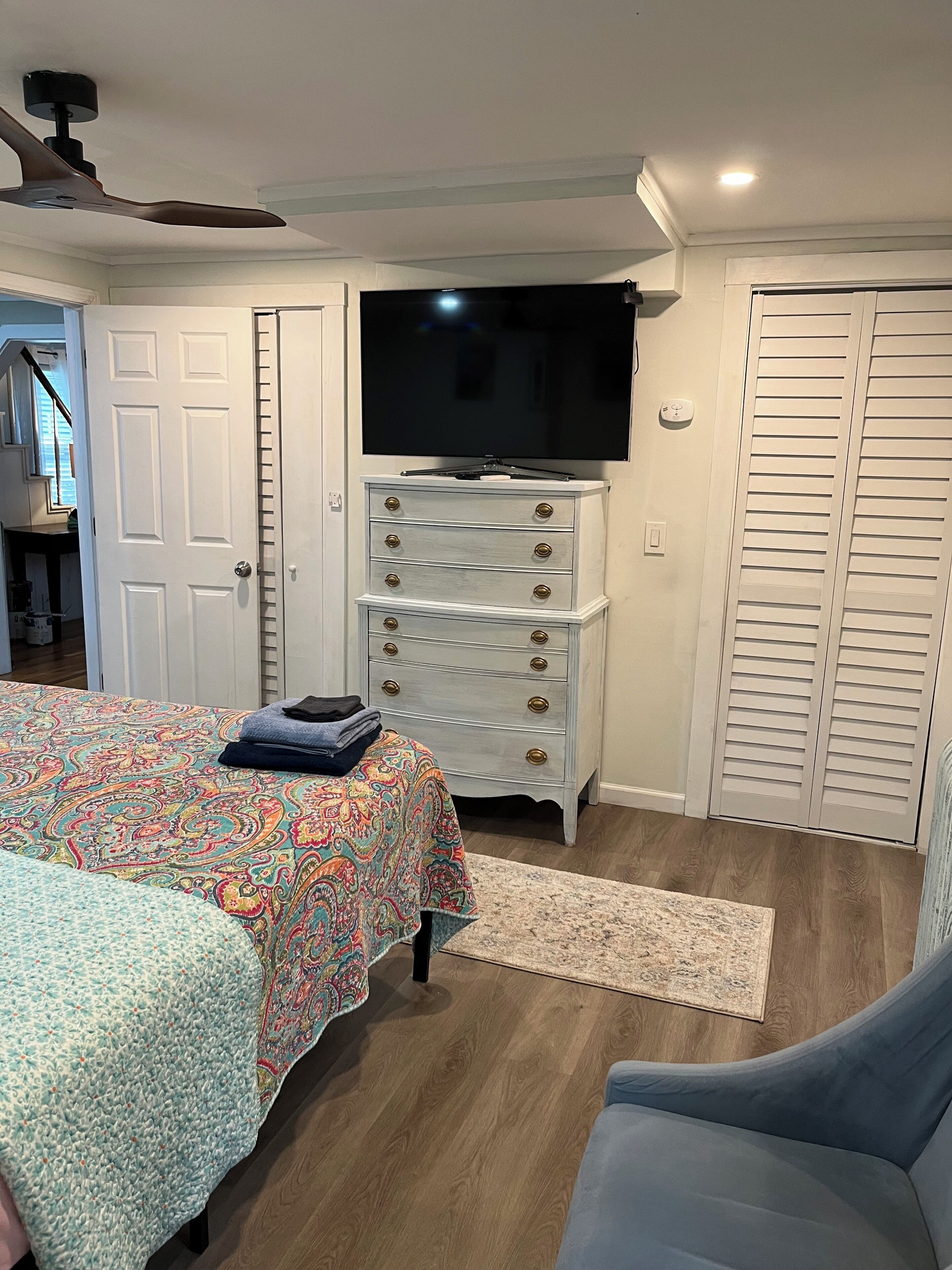 A bedroom with a bed, a dresser, a television, and a closet.