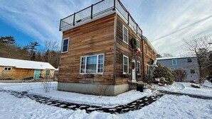 Ein zweigeschossiges Holzhaus mit Balkon, Veranda und einem schneebedeckten Vorgarten.