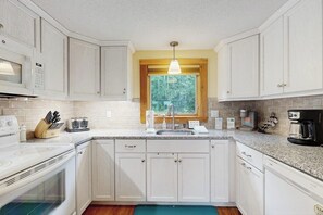 A kitchen with white cabinets, a window, a built-in microwave, a toaster, and a coffee maker. - Charming Resort Condo w/ Amazing Views, Fast WiFi & Perfect Location (Bartlett)