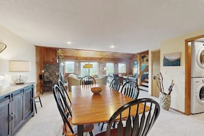A dining area with a wooden table and chairs, a stone fireplace, and a view of the outdoors. - Charming Resort Condo w/ Amazing Views, Fast WiFi & Perfect Location (Bartlett)