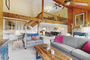 A spacious living area with a high ceiling, wooden beams, a staircase, and a dining area. - Charming Resort Condo w/ Amazing Views, Fast WiFi & Perfect Location (Bartlett)