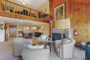 A spacious living area with a fireplace, a dining area, and a kitchen in the background. - Charming Resort Condo w/ Amazing Views, Fast WiFi & Perfect Location (Bartlett)