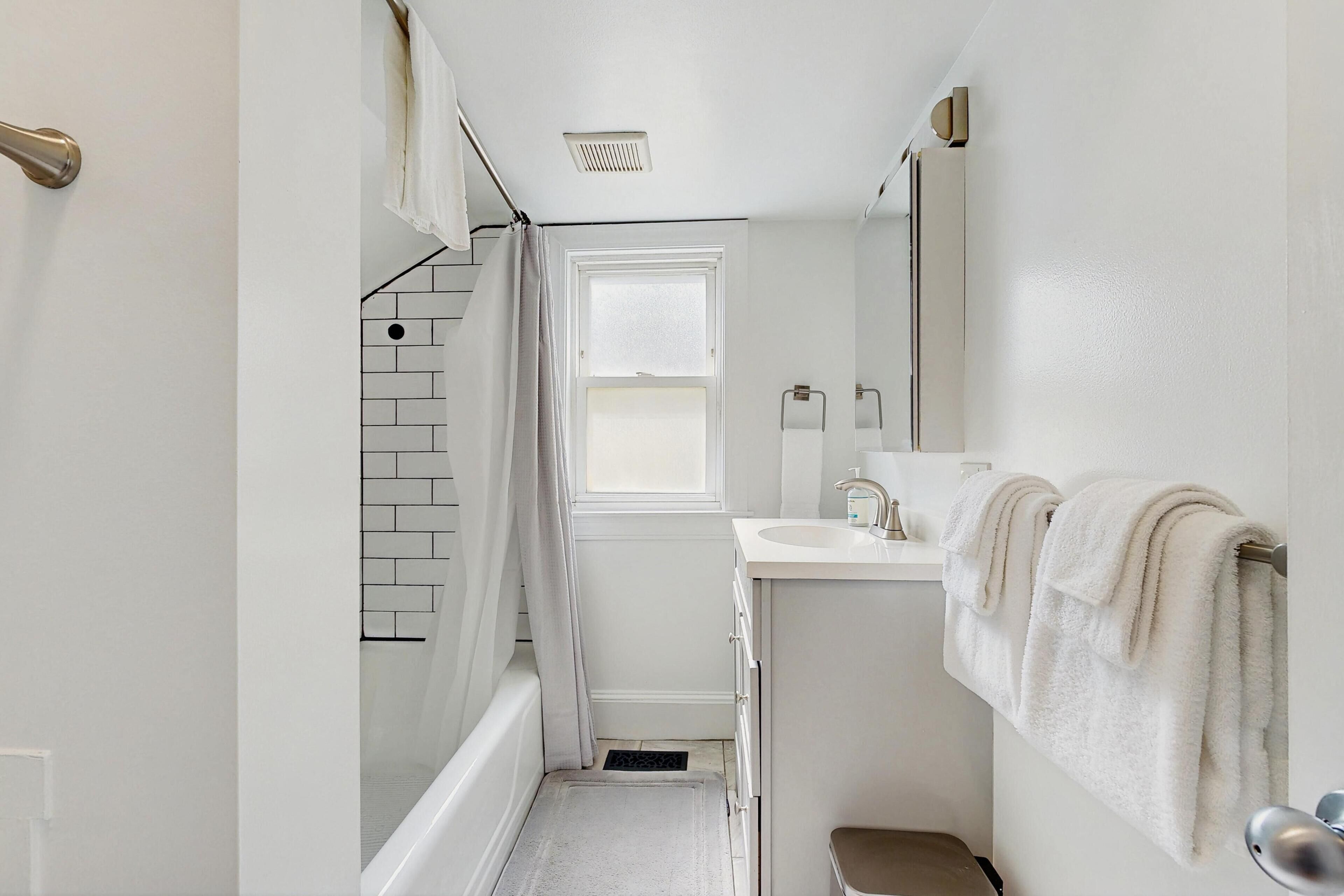 A narrow bathroom with a white sink, a mirror, and a towel rack.