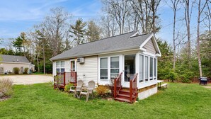 Une maison de plain-pied avec un porche à l’avant, une petite terrasse et une pelouse.