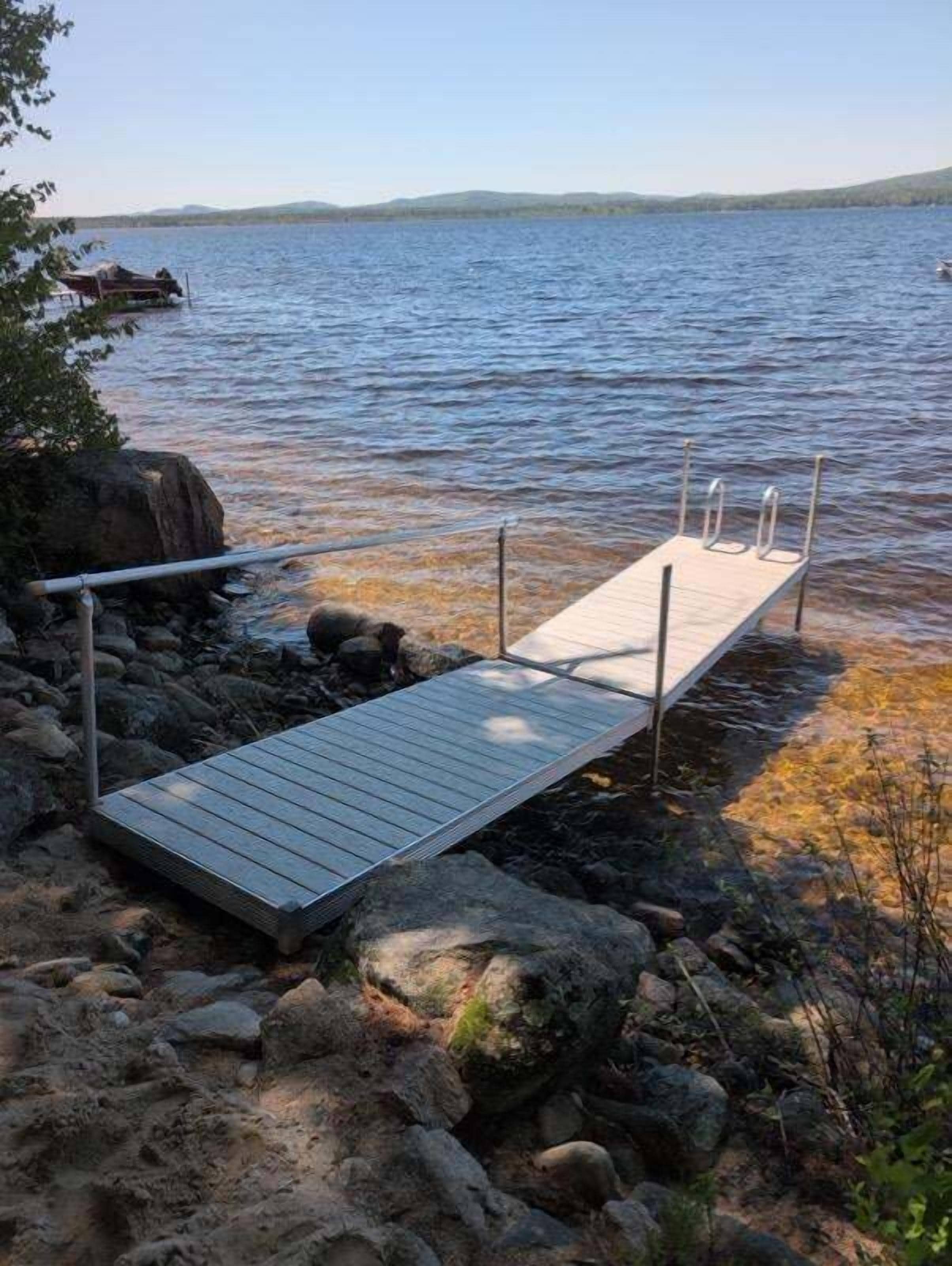 A wooden dock extending into a lake with a clear sky above.