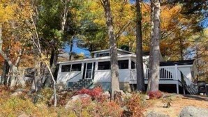A house with a porch, surrounded by trees and rocks.