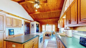 Una cocina con armarios de madera, una isla central y un ventilador de techo.