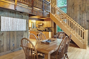 Ein Holzinterieur mit Esstisch, Stühlen, einer Küche und einer Treppe.