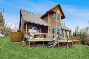 A two-story wooden house with a deck and a covered porch.