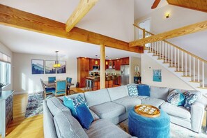 A spacious living room with a large sectional sofa, a wooden staircase, and a kitchen in the background. - New Slopeside Home at Black Mountain w/ Mountain Views, AC, Deck, Grill & WiFi (Jackson)