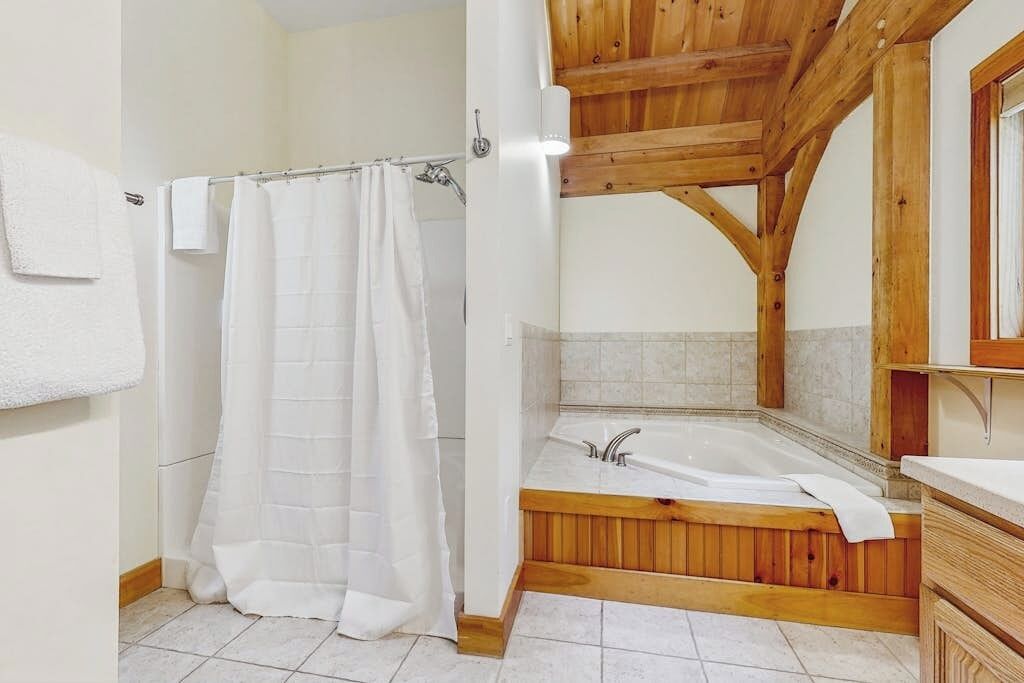 A bathroom with a wooden ceiling, a bathtub, and a shower curtain.