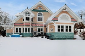 A large, multi-story house with a steeply pitched roof, multiple chimneys, and a symmetrical facade.