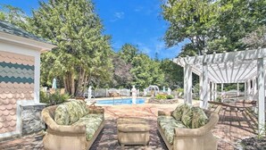 Un patio con mobiliario de mimbre, piscina y pérgola.