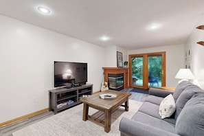 A living room with a TV, a fireplace, a sofa, and a coffee table. - Homey Mountain Retreat: close to skiing and all season outdoor adventures (Lincoln)
