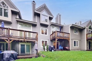 A multi-story residential building with a deck on the second floor, a covered outdoor seating area, and a front door with a glass door. - Homey Mountain Retreat: close to skiing and all season outdoor adventures (Lincoln)