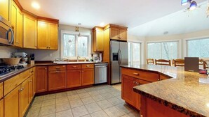 Una cocina con armarios de madera, un refrigerador de acero inoxidable, un lavavajillas y una encimera de granito.