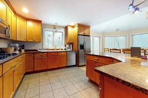 A kitchen with wooden cabinets, a stainless steel refrigerator, a dishwasher, and a granite countertop. - Cozy, Dog-Friendly Home with High-Speed WiFi & Deck (Jackson)