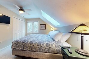 A bedroom with a bed, a ceiling fan, a lamp, a TV, and a skylight. - Cozy, Dog-Friendly Home with High-Speed WiFi & Deck (Jackson)