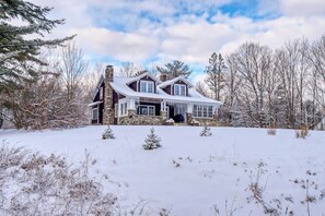 A large, two-story house with a stone facade, multiple windows, and a snow-covered roof. - Cozy home with  covered porch, & sun room - walk to shops/dining/bars (Bethlehem)