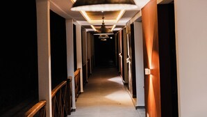 A hotel hallway with a ceiling light, wooden railings, and a tiled floor.