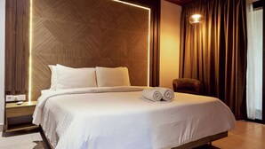 A modern bedroom with a large bed, wooden ceiling, and a nightstand.