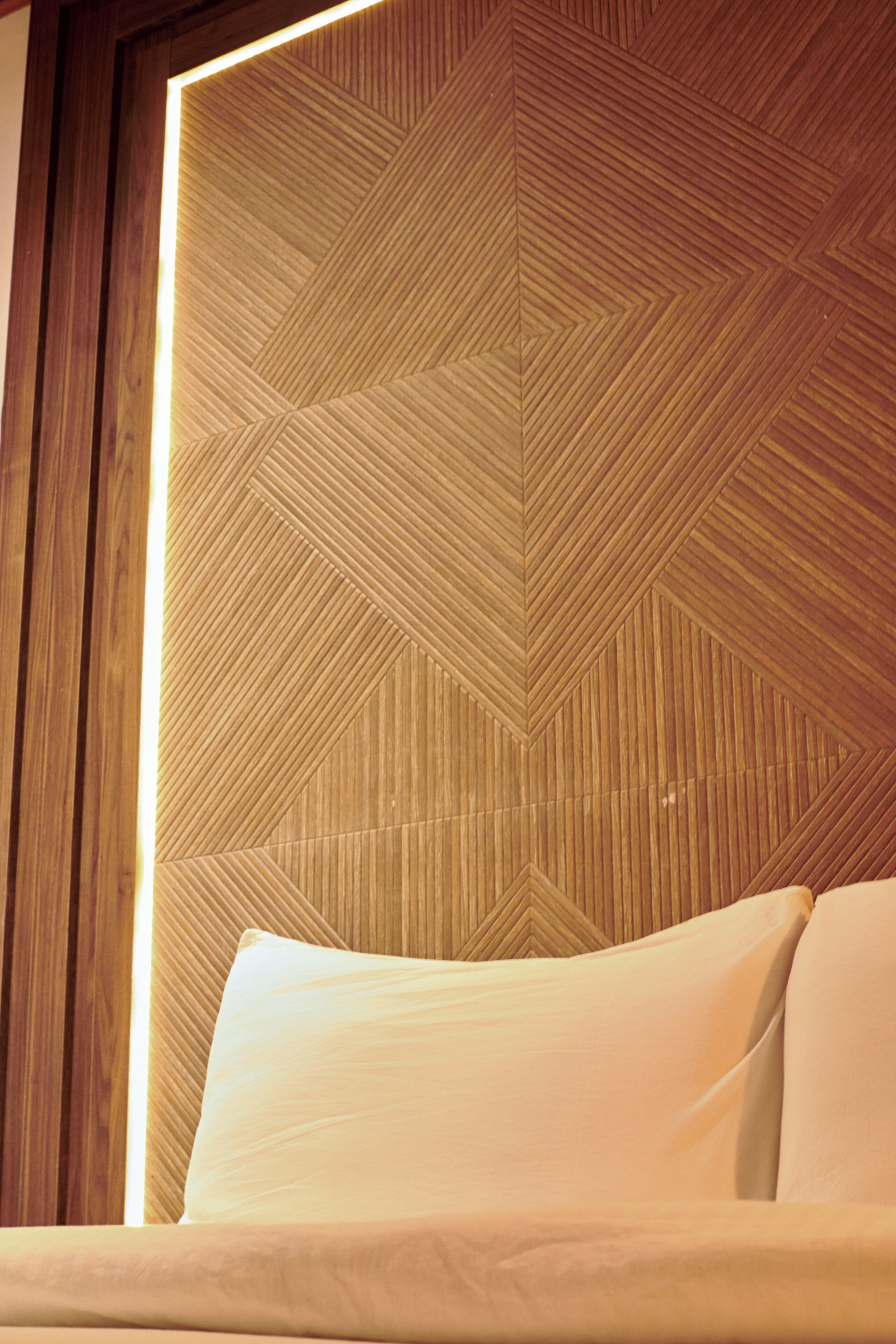 Una cama con cabecera de diseño geométrico y estructura de madera.