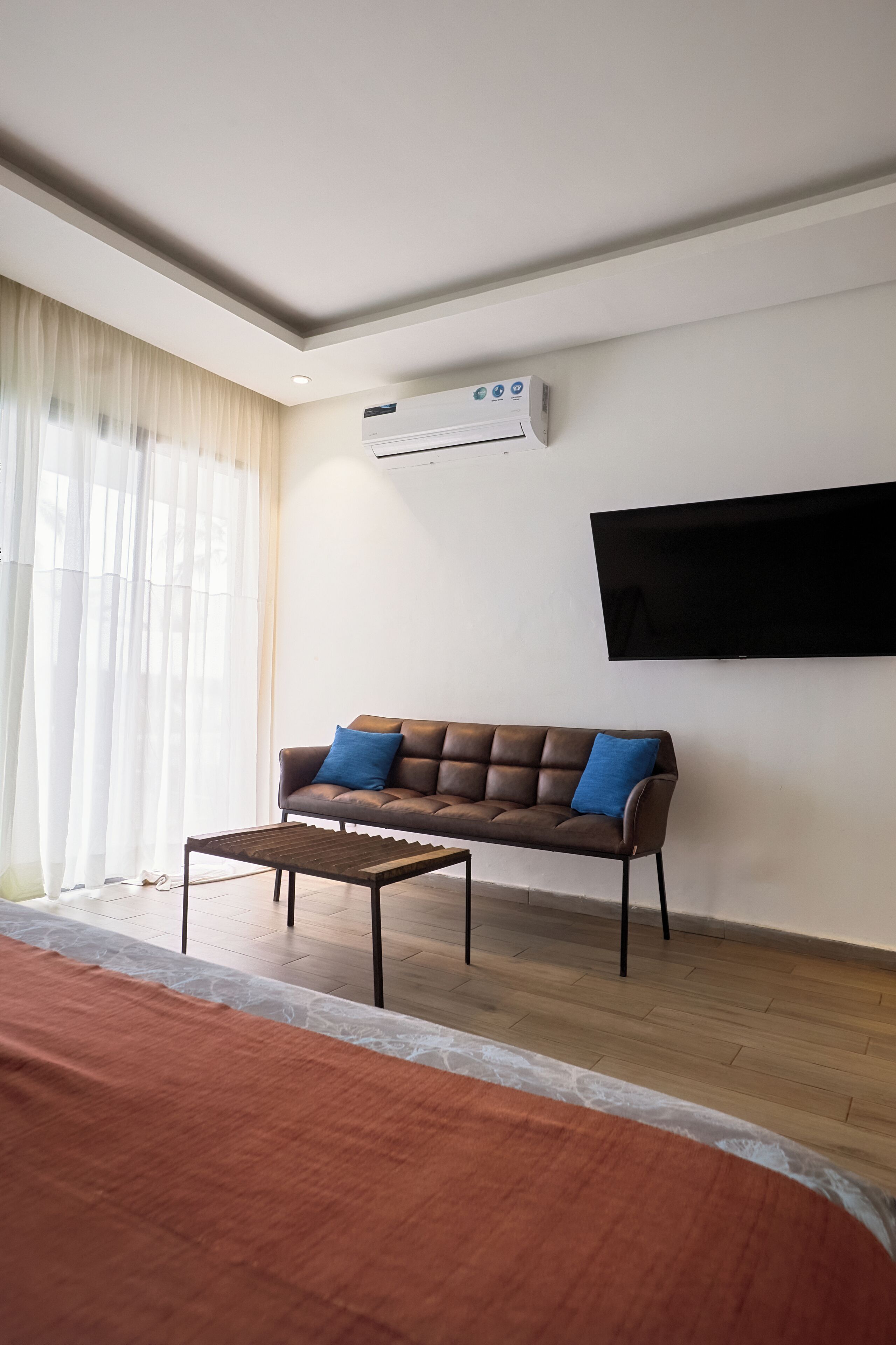 Una sala de estar con un sofá, una mesa de centro, un televisor de pantalla plana y un equipo de aire acondicionado.
