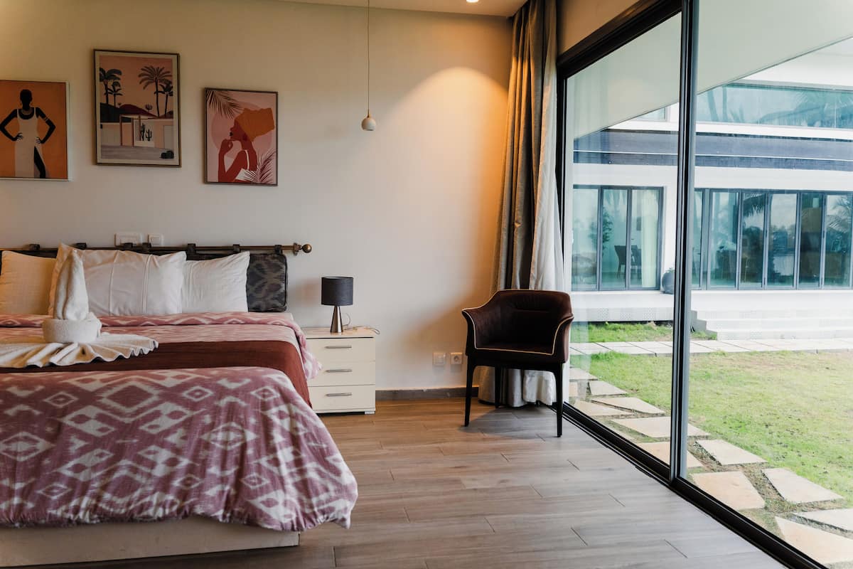 A bedroom with a large bed, a chair, a nightstand, and artwork on the wall.