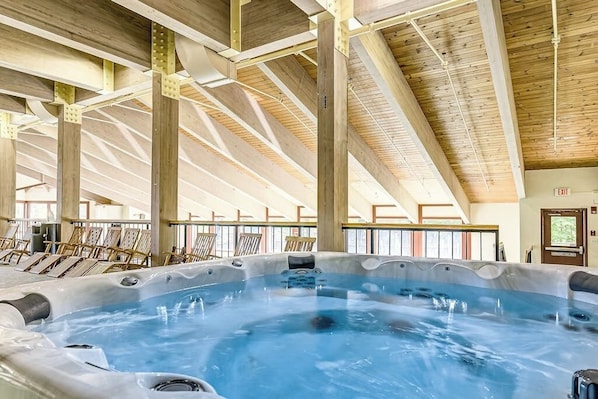 Un amplio jacuzzi interior con vigas de madera y un techo alto.